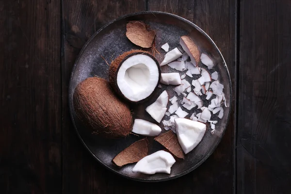 Cracked coconut on metal plate on rustic wooden table background Stock Image