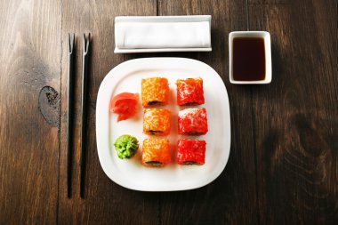 Plaka, soya sosu ve chopsticks ahşap arka plan üzerinde suşi rulo