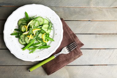 ahşap masa, üstten görünüm üzerinde salatalık, roka ve limon kabuğu ile yeşil salata