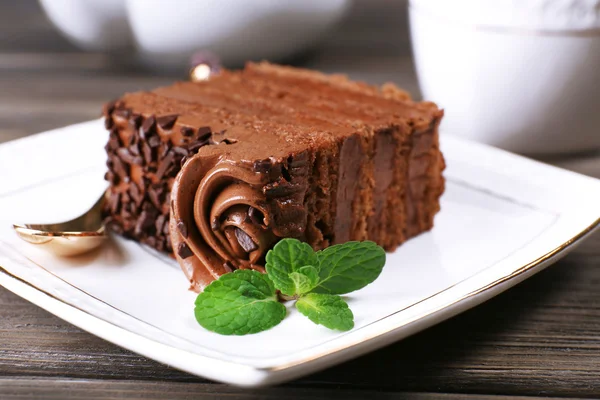 Tasty piece of chocolate cake with mint on wooden table background — Stock Photo, Image