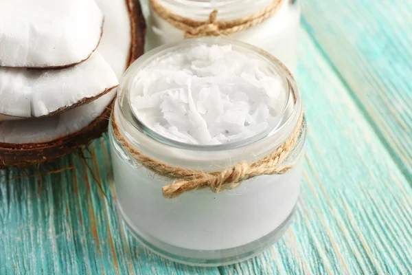 Aceite de coco fresco en cristalería sobre fondo de mesa de madera de color — Foto de Stock