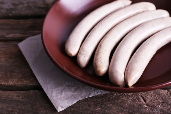 Salsichas cozidas na placa no fundo da mesa de madeira — Fotografia de Stock