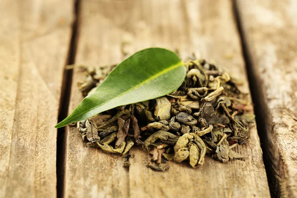 Zelený čaj s listy na starý dřevěný stůl — Stock fotografie