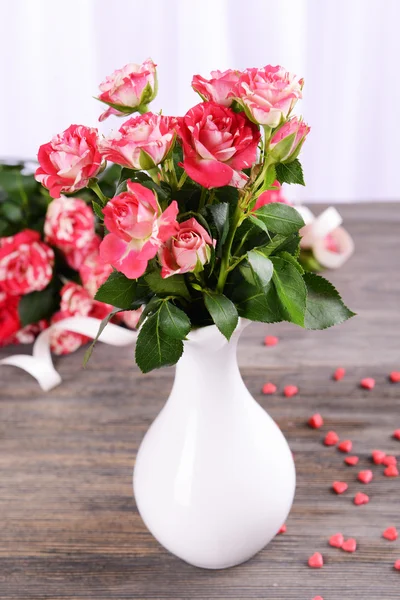 Mooie rozen in vaas op tafel op lichte achtergrond — Stockfoto