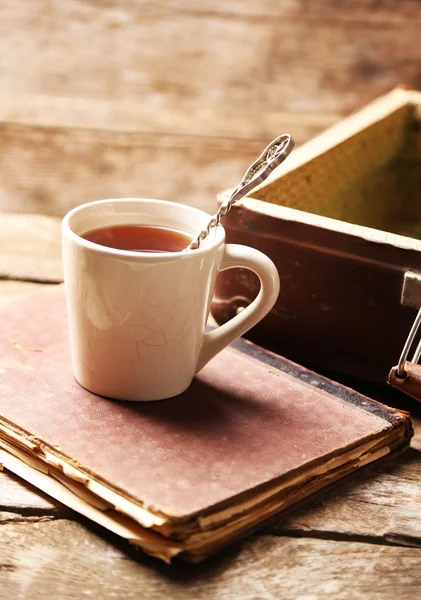 Eski kitaplar ve çay bardağı ahşap arka plan üzerinde eski tahta bavulla — Stok fotoğraf