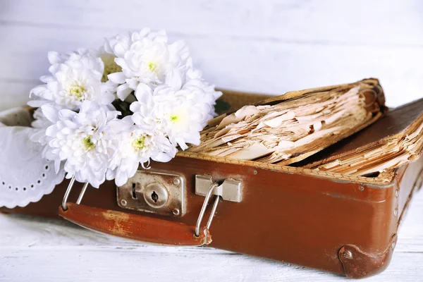 Oude houten koffer met oude boeken en bloemen op houten achtergrond — Stockfoto