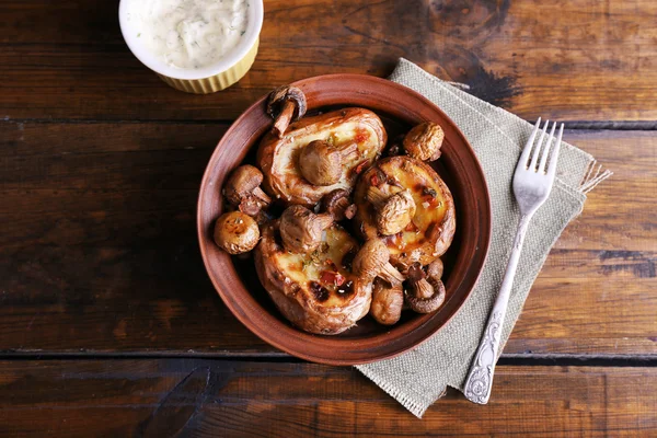 Baked potatoes with mushrooms in bowl and sauce on table close up — Stock Photo, Image