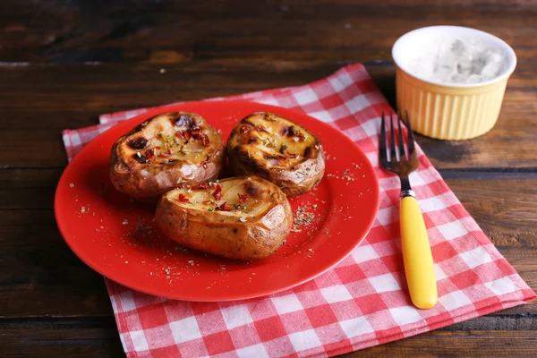 Baked potatoes on plate and sauce on table close up — Stock Photo, Image