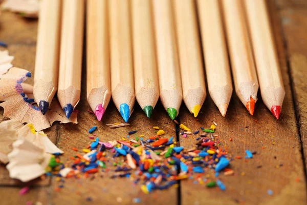 Wooden colorful pencils with sharpening shavings, on wooden table — Stock Photo, Image