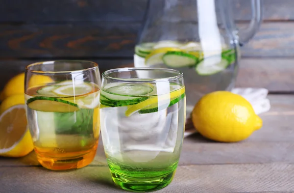 Fresh water with lemon and cucumber in glassware on wooden background — Stock Photo, Image