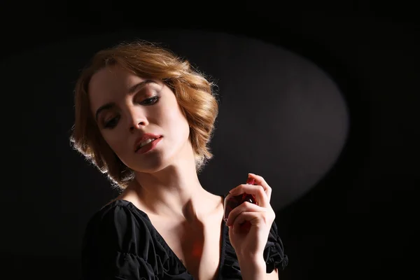 Belle jeune femme avec bouteille de parfum sur fond noir — Photo