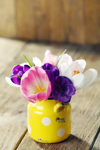 Hermosas flores de primavera en maceta amarilla sobre fondo de madera — Foto de Stock