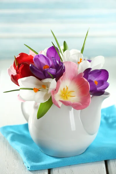 Bellissimi fiori primaverili su tavolo di legno su sfondo blu — Foto Stock