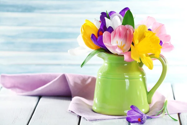 Bellissimi fiori primaverili su tavolo di legno su sfondo blu — Foto Stock