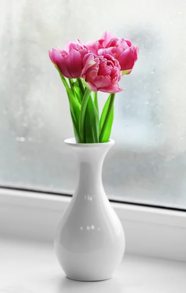 Schöne rosa Tulpen in der Vase auf der Fensterbank Hintergrund — Stockfoto