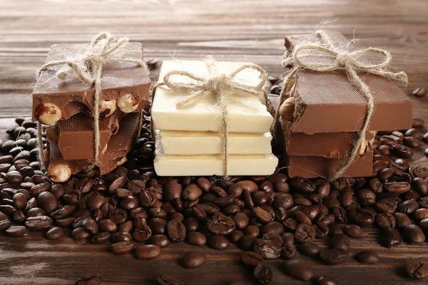 Pilha de chocolate amarrado com grãos de café na mesa de madeira, close-up — Fotografia de Stock