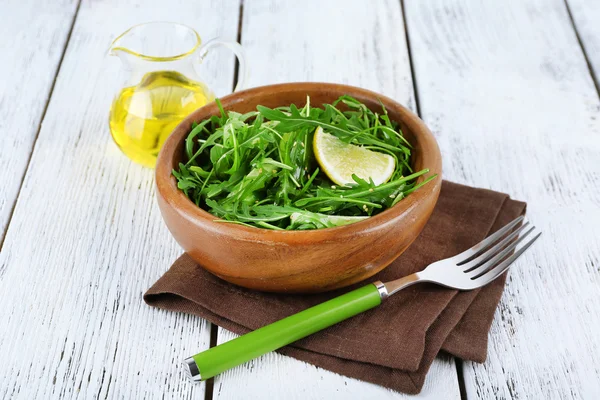 Tigela de salada verde e limão fatiado no fundo de madeira — Fotografia de Stock