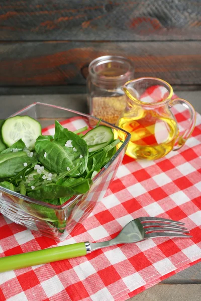 Tigela de vidro de salada verde com pepino e espinafre na mesa de madeira com guardanapo, close-up — Fotografia de Stock