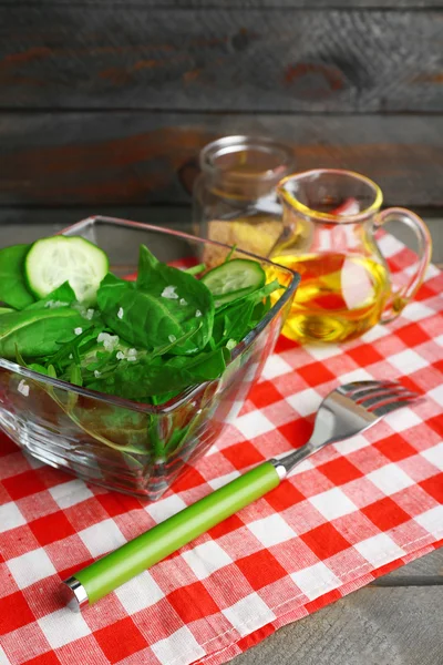 Cuenco de vidrio de ensalada verde con pepino y espinacas en mesa de madera con servilleta, primer plano —  Fotos de Stock