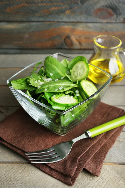 玻璃碗的绿色沙拉，黄瓜，菠菜木制背景 — 图库照片