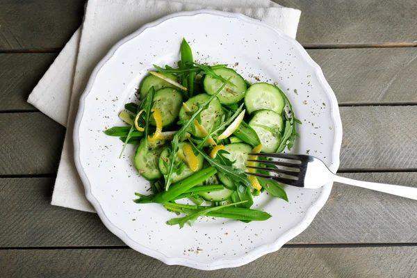 Ensalada verde con pepino, rúcula y cáscara de limón en mesa de madera, vista superior —  Fotos de Stock