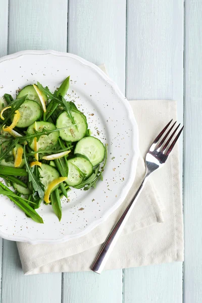 Ensalada verde con pepino, rúcula y cáscara de limón en mesa de madera, vista superior —  Fotos de Stock