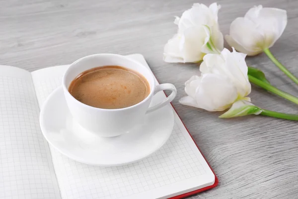 Krásné tulipány s deník a šálek kávy na dřevěné pozadí — Stock fotografie