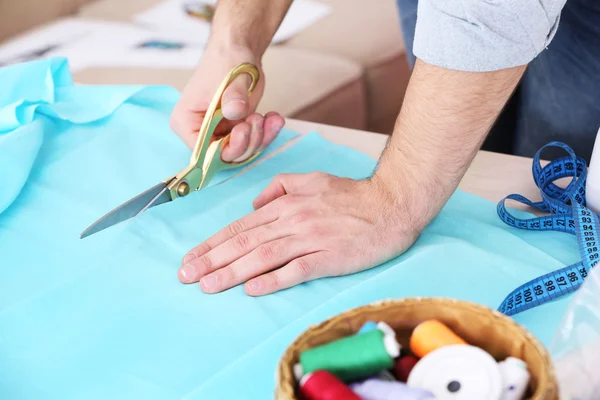 Masculino costureira corte tecido na mesa — Fotografia de Stock