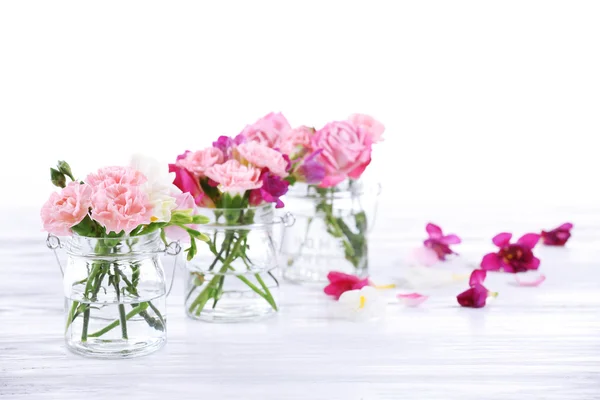 Hermosas flores de primavera en botellas de vidrio aisladas en blanco —  Fotos de Stock