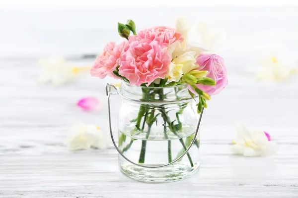 Bellissimi fiori primaverili in bottiglia di vetro su sfondo di legno — Foto Stock
