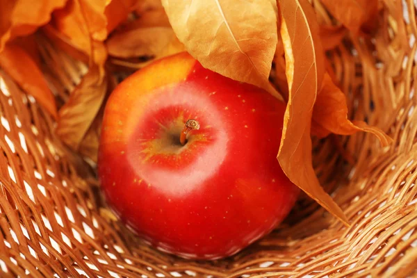 Manzana con hojas secas en canasta de mimbre, primer plano —  Fotos de Stock
