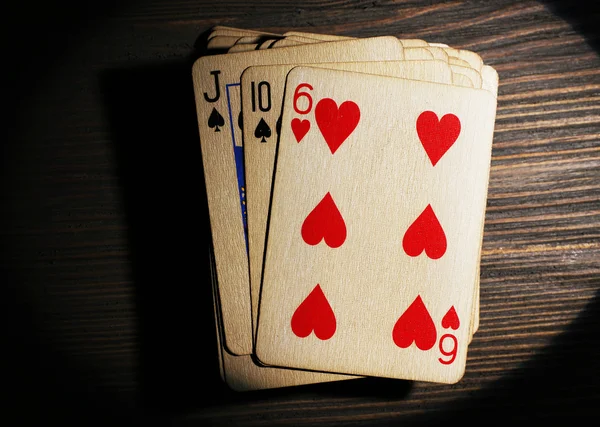 Stack of playing cards in light on wooden table, top view — Stock Photo, Image