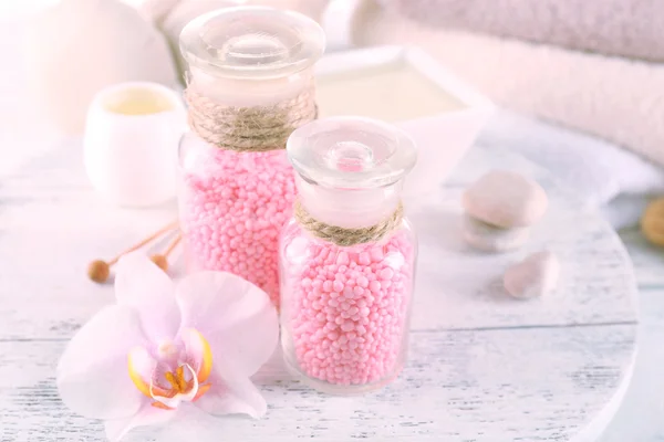 Bouteilles en verre avec sel de mer de spa de couleur sur la table en bois, gros plan — Photo