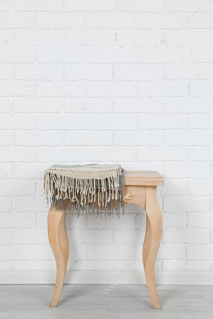 Wooden chair with plaid on white brick wall background