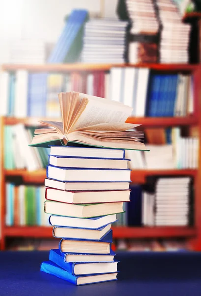 Stack of books on table on bookshelves background — Stock Photo, Image