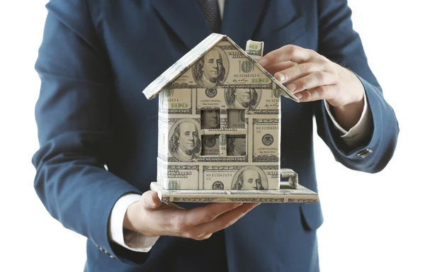 Beyaz arka plan üzerinde izole erkek elinde para yapılmış ev modeli — Stok fotoğraf