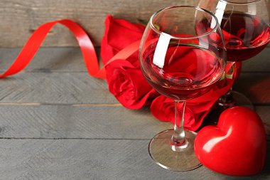 Gözlük, kırmızı gül ve dekoratif kalp ahşap arka plan üzerinde kırmızı şarap ile kompozisyon