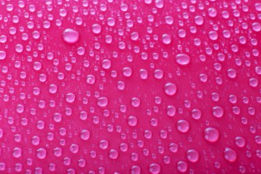 Pembe bir arka plan üzerinde camına su damlaları