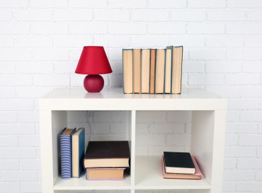 Kitap ve tuğla duvar arka lamba ile ahşap raf