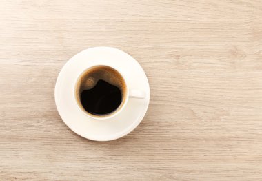 Bir fincan kahve, ahşap masa, üst manzara.