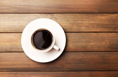 Bir fincan kahve, ahşap masa, üst manzara.