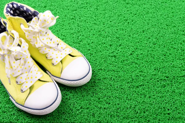Zapatillas de deporte sobre fondo de alfombra verde —  Fotos de Stock
