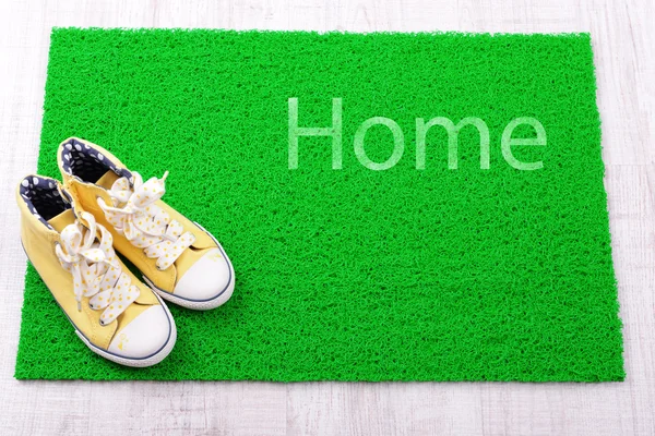 Sneakers and green carpet on floor — Stock Photo, Image