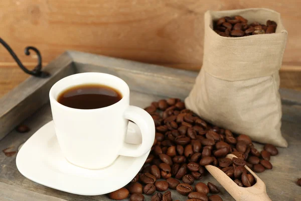 Tasse de café avec des grains sur plateau et fond en bois rustique — Photo