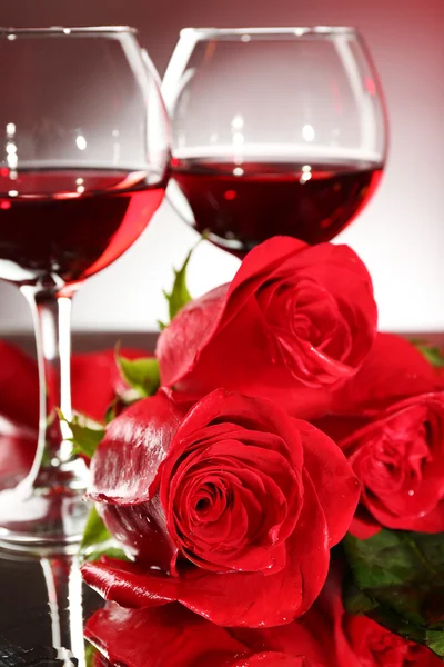 Composição com vinho tinto em copos, rosa vermelha e coração decorativo em fundo colorido — Fotografia de Stock