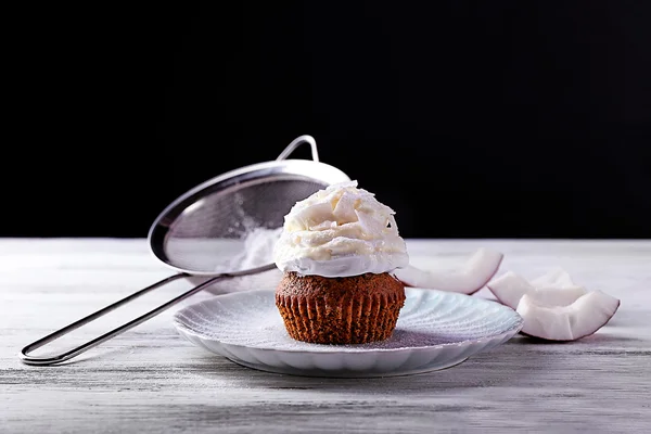 Delizioso cupcake al cocco con crema sul tavolo di legno di colore e sfondo scuro — Foto Stock