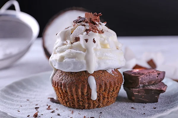 Köstliche Kokos-Cupcake mit Sahne und Schokolade Chips auf farbigem Holztisch und dunklem Hintergrund — Stockfoto
