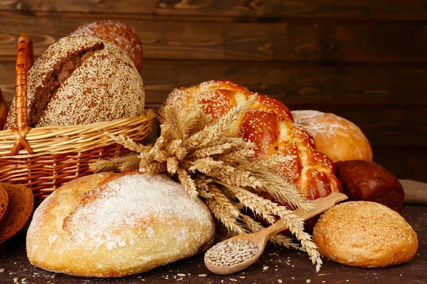 Различные хлеба с ушами и семена подсолнечника на деревянном фоне — стоковое фото