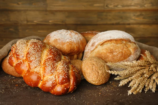 Different bread with ears on wooden background — Stock Photo, Image