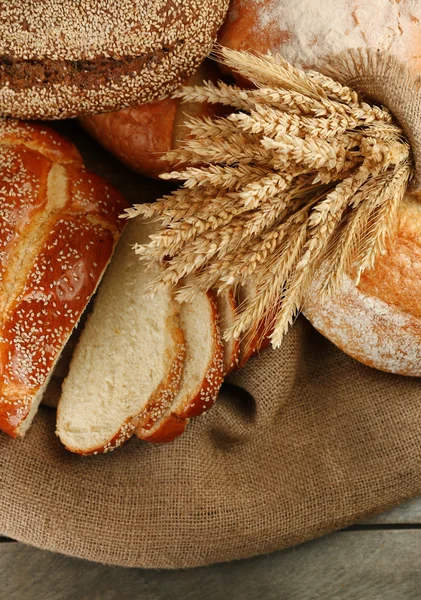 Different bread with ears on sackcloth background — Stock Photo, Image